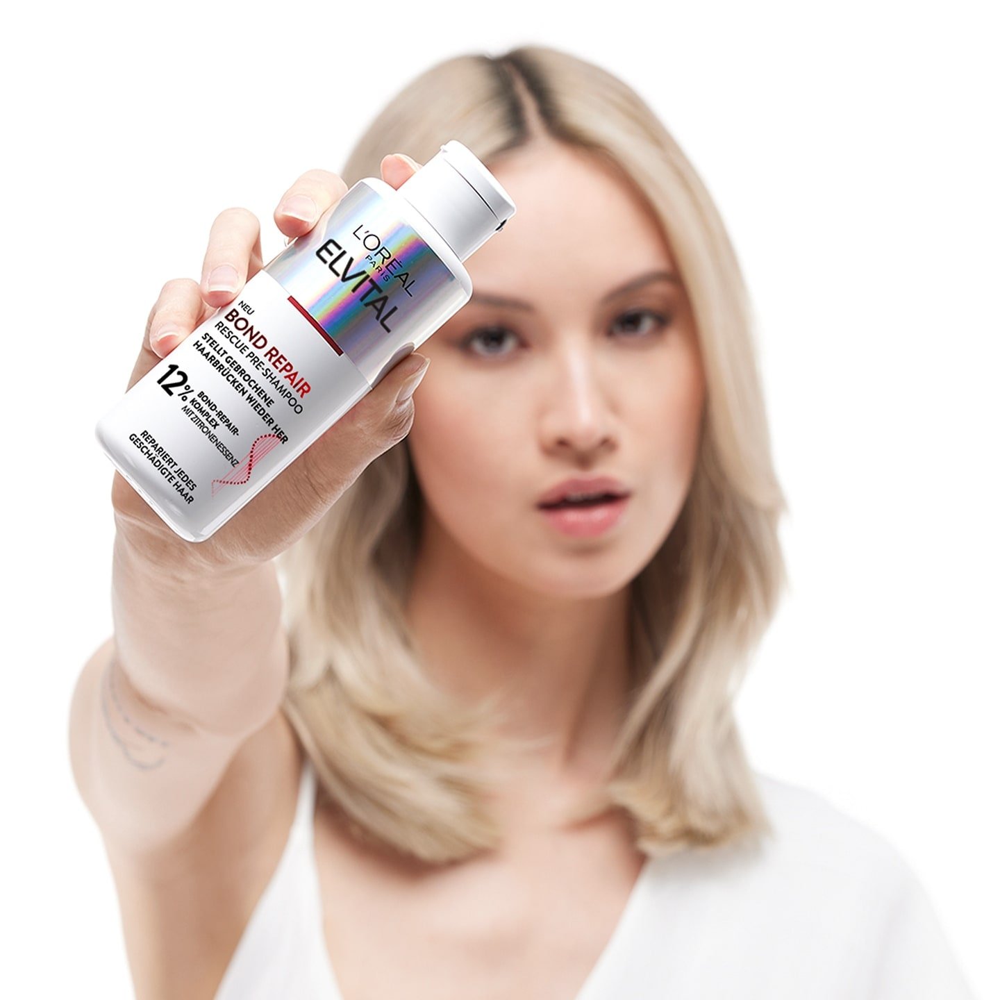 Model haelt Loreal Elvital Bond Repair Pre-Shampoo in ihren Haenden